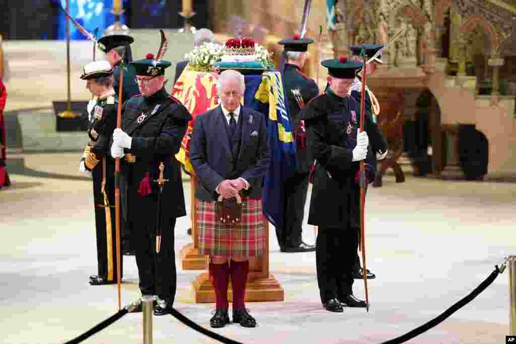 Britain's King Charles III, center, and other members of the royal family hold a vigil at the coffin of Queen Elizabeth II at St. Giles' Cathedral, Edinburgh, Scotland, as members of the public walk past.