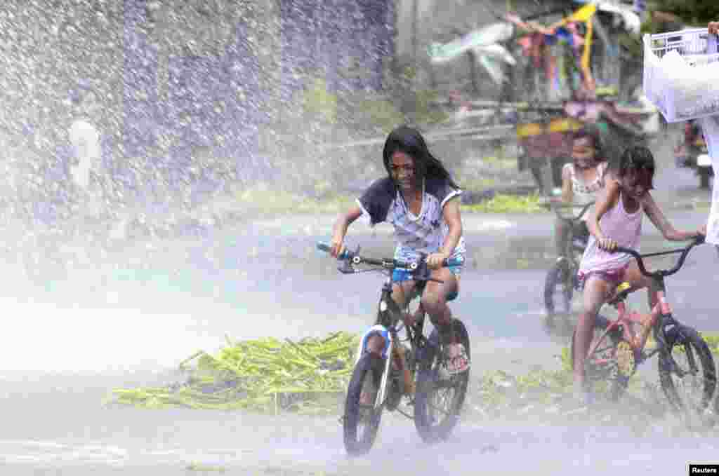 Girls ride on bicycles as they are splashed with water from strong waves in a coastal village as Typhoon Haiyan battered Bayog town in Los Banos, Laguna, south of Manila, Nov. 8, 2013. 