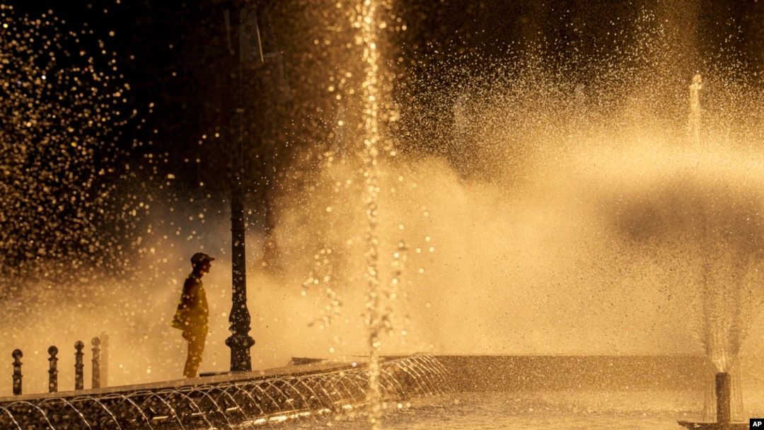 A municipal worker cools off next to a city fountain in Bucharest, Romania, July 11, 2024, as temperatures exceeded 39 degrees Celsius.