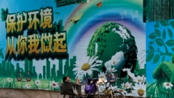 一名工人在北京的一面"保護環境從你我做起"的宣傳畫前休息。（2017年6月5日）