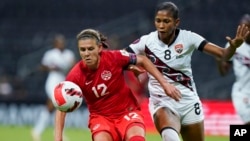 FILE - Canada's Christine Sinclair (12) and Trinidad and Tobago's Victoria Swift compete for the ball during a CONCACAF women's championship soccer match in Monterrey, Mexico, July 5, 2022.