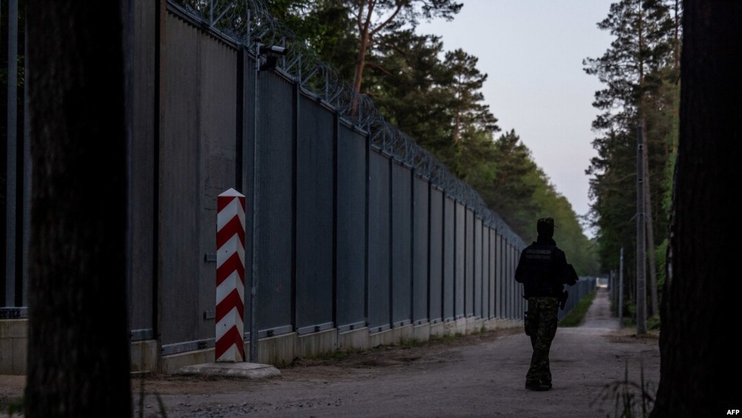 FILE - A border guard patrol along the border wall at Polish - Belarus border not far from Bialowieza, eastern Poland, May 29, 2023. 