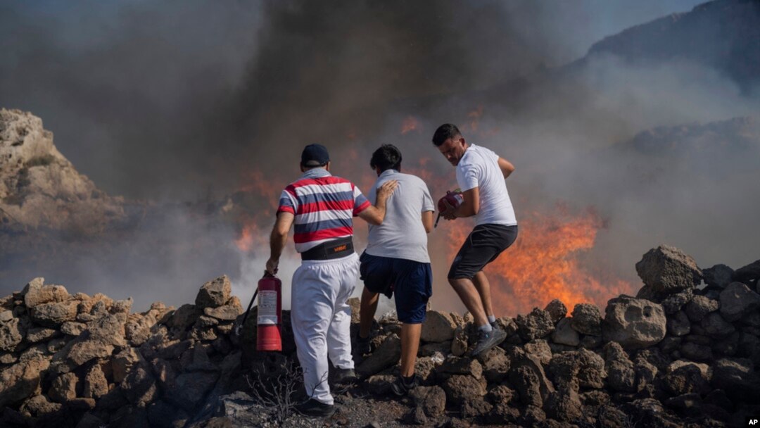 FILE - Local residents try to extinguish a fire, near the seaside resort of Lindos, on the Aegean Sea island of Rhodes, southeastern Greece, on July 24, 2023.