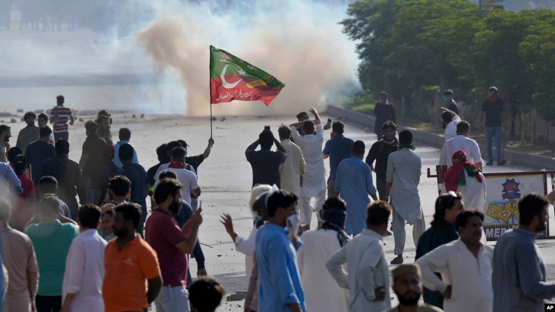 FILE - Supporters of Pakistan's former Prime Minister Imran Khan block a road as police fire tear gas to disperse them during a protest in support of Khan in Karachi, Pakistan, May 9, 2023. 