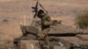 An Israeli soldiers walks on the top of a stationed tank near the border with Lebanon, in Israel, Oct. 14, 2023. 