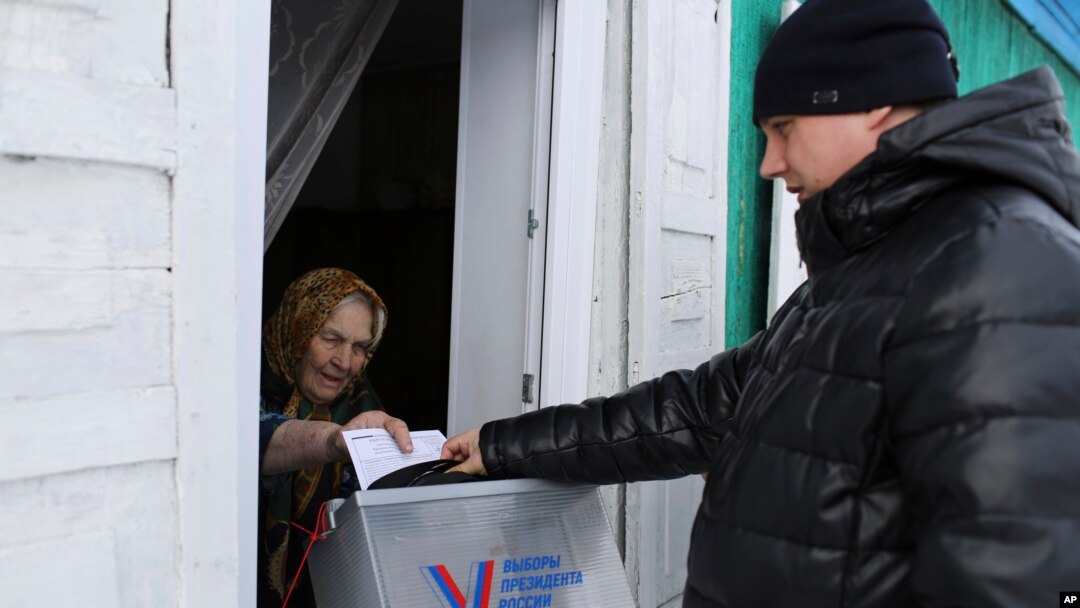 An elderly woman votes during the Russian presidential election via a mobile election committee that visits people unable to physically visit a polling station, in Nikolayevka village outside the Siberian city of Omsk, east of Moscow, Russia, March 16, 2024.