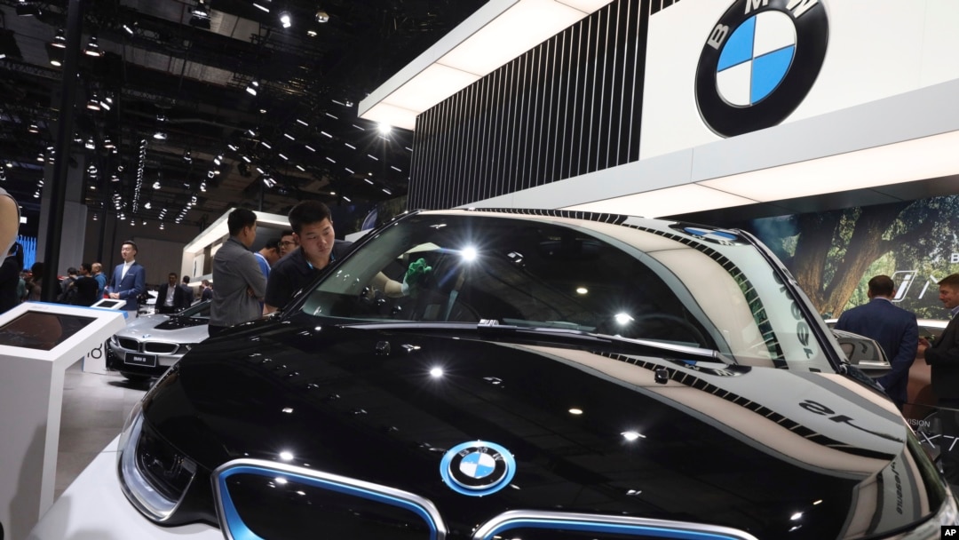 FILE - A worker cleans an electric vehicle at the BMW booth during the Auto Shanghai 2019 show in Shanghai, Apr. 17, 2019. BMW was recalling more than 1.3 million vehicles in China that might have Takata airbag inflators.