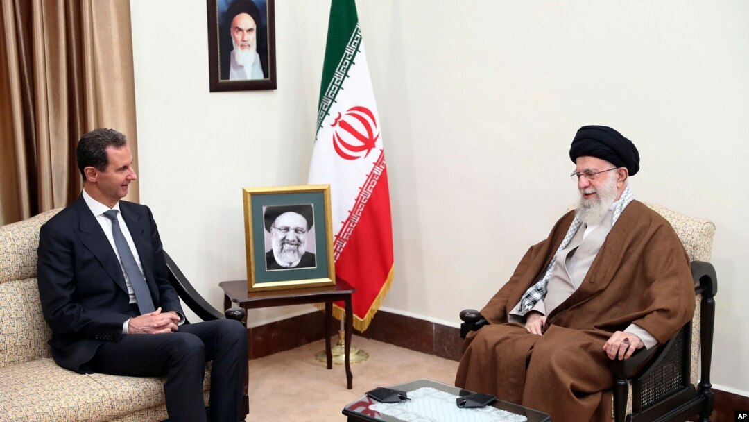 Iran's Supreme Leader Ayatollah Ali Khamenei, right, speaks with Syrian President Bashar Assad during their meeting in Tehran, May 30, 2024. A portrait of the late President Ebrahim Raisi is seen between them. (Office of the Iranian Supreme Leader via AP)