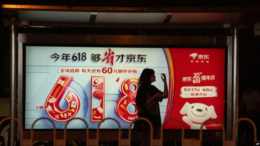 A woman stands near an advertisement for the annual June 18 Shopping Festival in Beijing, June 18, 2023. 