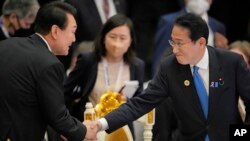 南韓總統尹錫悅(左)與日本首相岸田文雄2022年11月13日在金邊舉行的東盟-東亞峰會上握手致意。