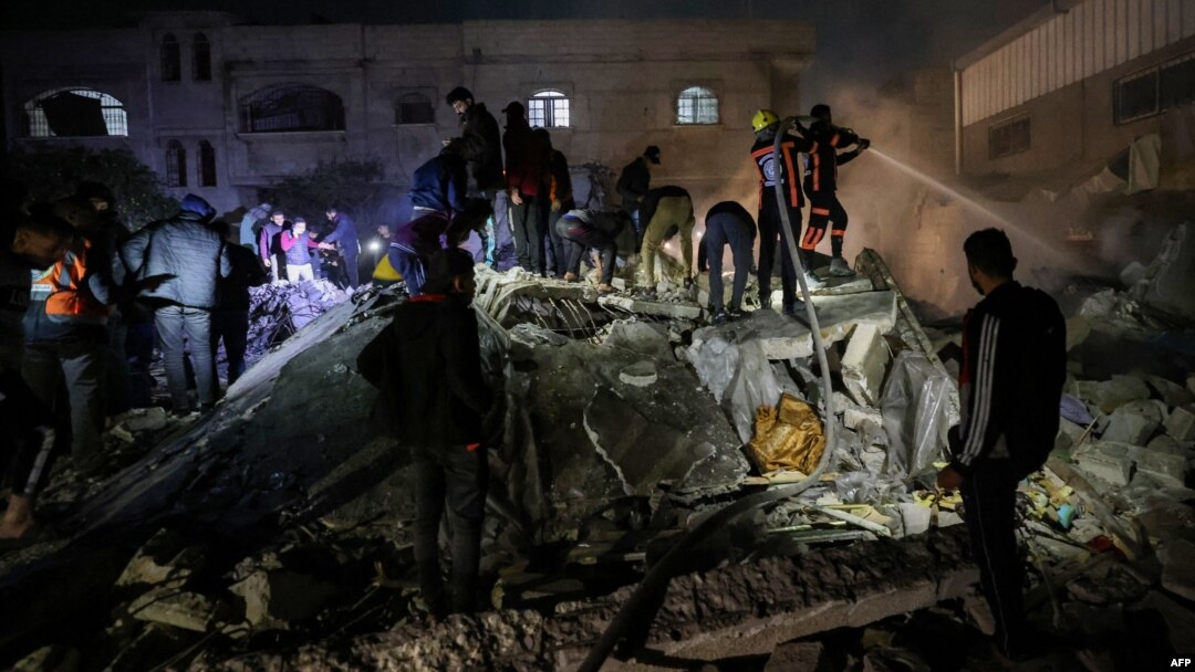 Firefighters and civilians gather at the rubble of a building following Israeli bombardment in Rafah, in the southern Gaza Strip, on Dec. 18, 2023, amid continuing battles between Israel and the Palestinian militant group Hamas.