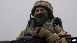 A Ukrainian marine holds an AK-47 at the front line close to the Dnipro river near Kherson, Ukraine, Oct. 14, 2023. 