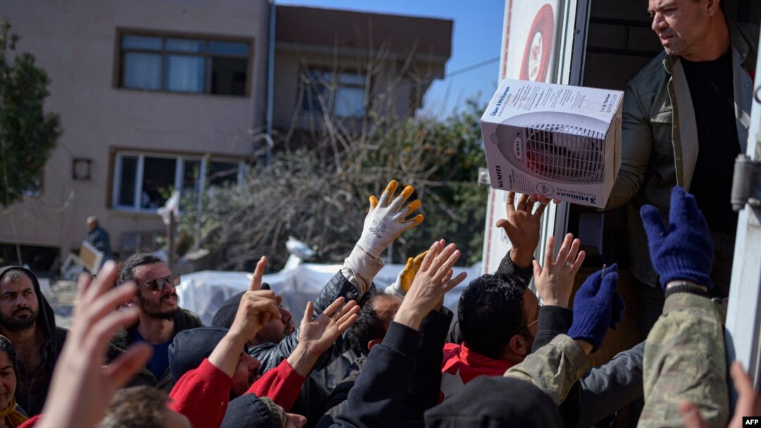 FILE - Residents grab food, clothes and household items delivered from the back of a truck in Samandag, south of Hatay, Turkey, Feb. 16, 2023, ten days after a 7.8-magnitude quake struck the border region of Turkey and Syria. 