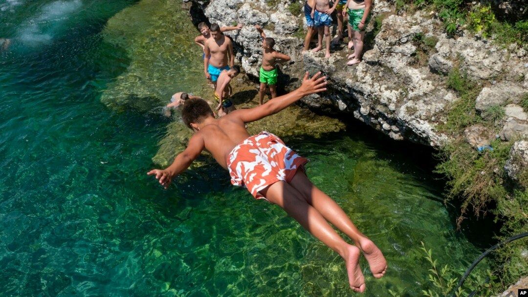 A boy dives into the Cijevna river near Montenegro's capital of Podgorica, as temperatures soared to 36 degrees Celsius on July 11, 2024.