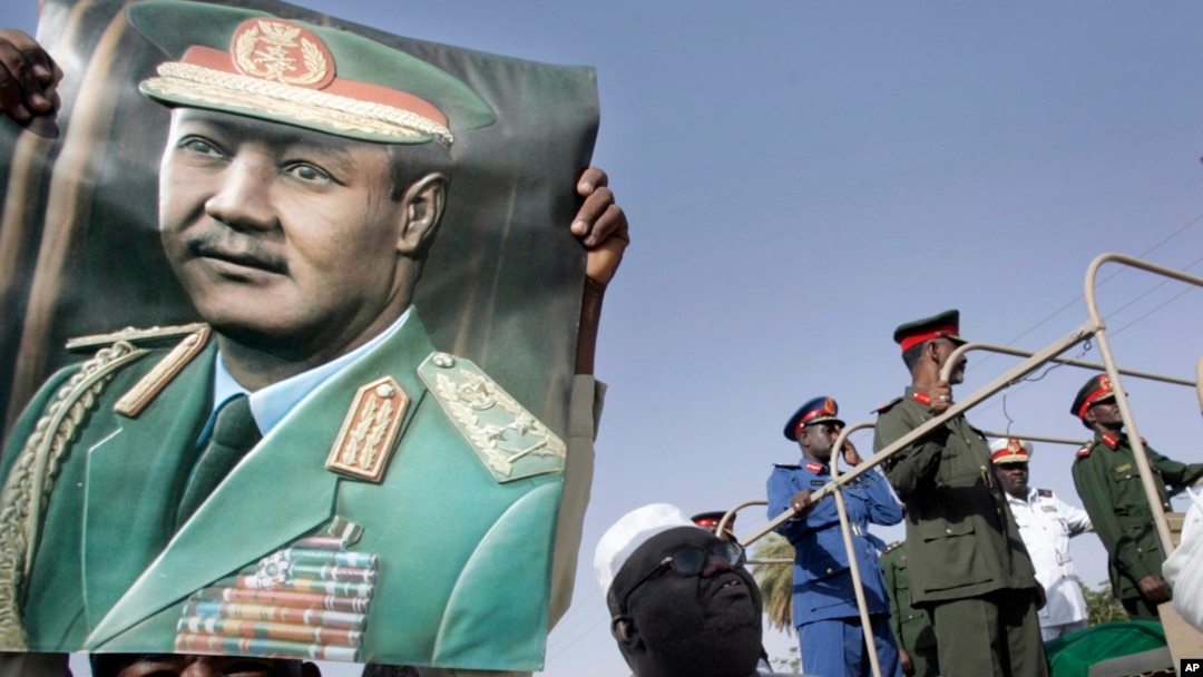 FILE - A man holds a poster showing former Sudanese President Jaafar al-Nimeiri, who became Sudan's president in 1969 and was overthrown in a bloodless coup in 1985, during his military funeral in Omdurman, Khartoum, May 31, 2009.