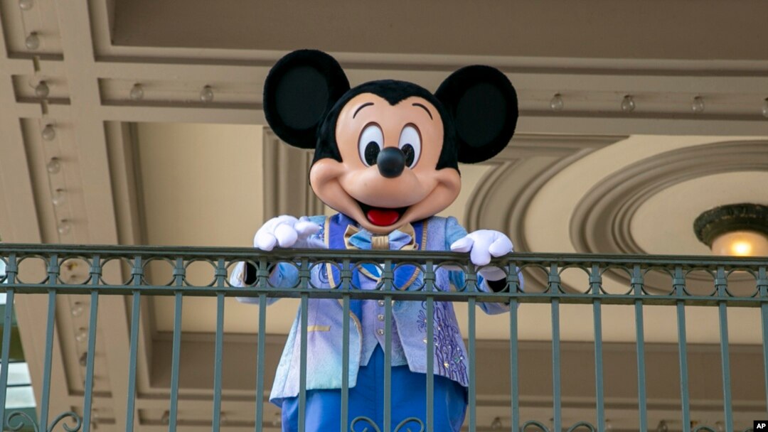 FILE - An actor dressed as Mickey Mouse greets visitors at the entrance to Magic Kingdom Park at Walt Disney World Resort, April 18, 2022, in Lake Buena Vista, Fla. 