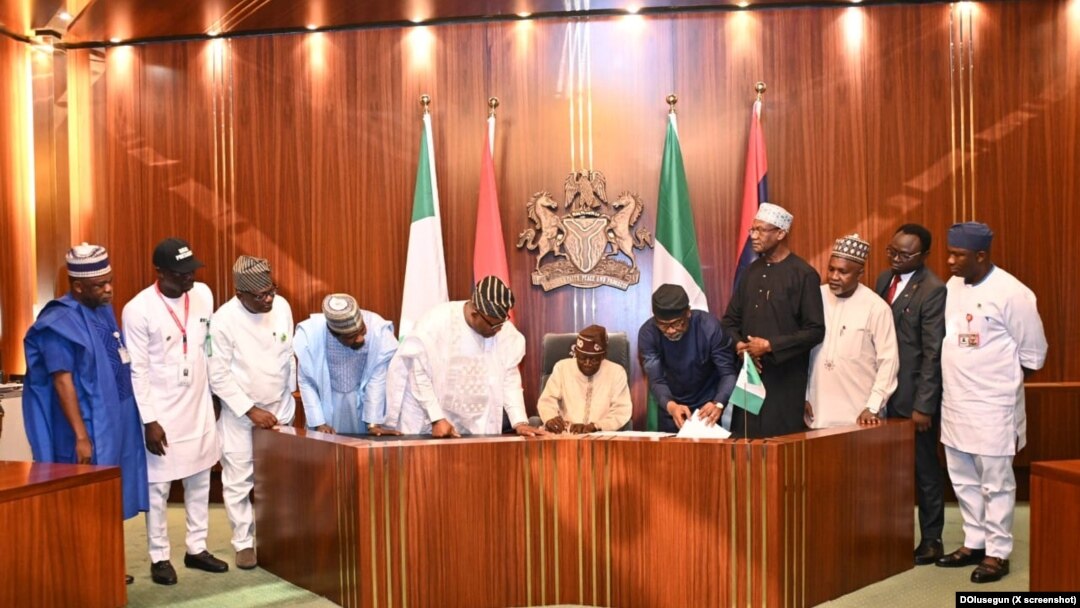 Shugaba Bola Tinubu a zagaye da wasu jami'in gwamnatinsa yayin da ya rattaba hanu akan dokar rancen dalibai.