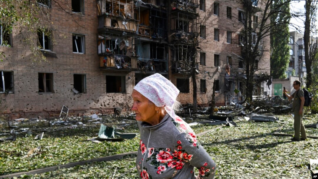 Yaşlı bir kadın 11 Ağustos 2024'te çekilen fotoğrafta Rusya'nın Kursk kentinde Ukrayna tarafından bombalandıktan sonra hasar gören bir apartmanın önünden geçiyor. 
