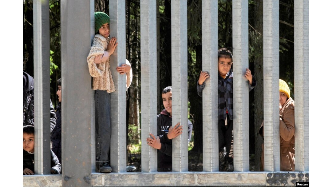 FILE - Migrants stand near the wall on Polish Belarusian border near Bialowieza, Poland, May 28, 2023.