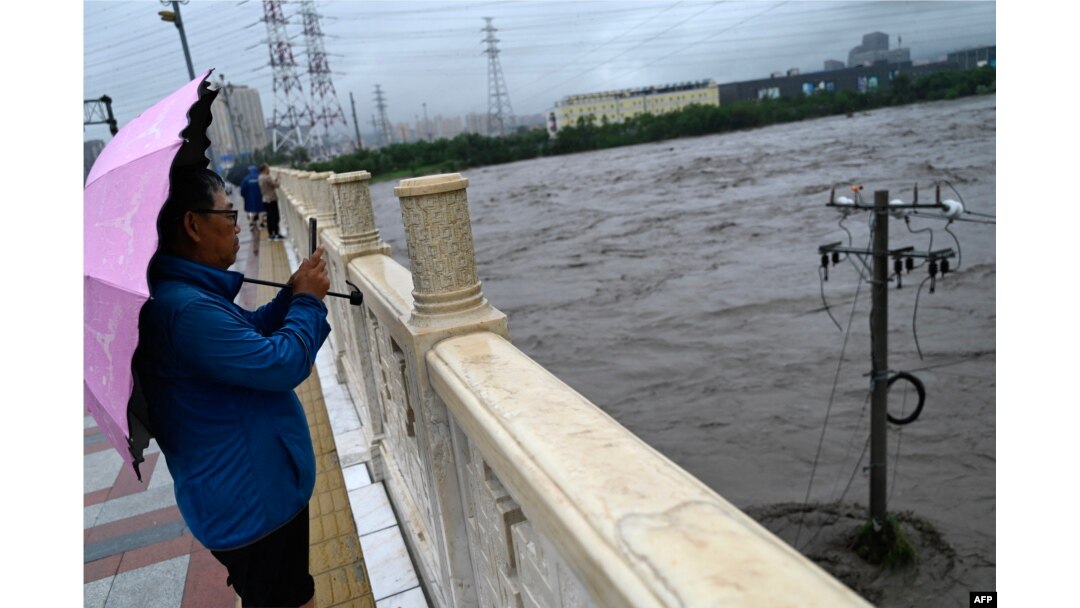 A man stands by the overflooded Yongding river, after heavy rains in Mentougou district in Beijing on July 31, 2023.