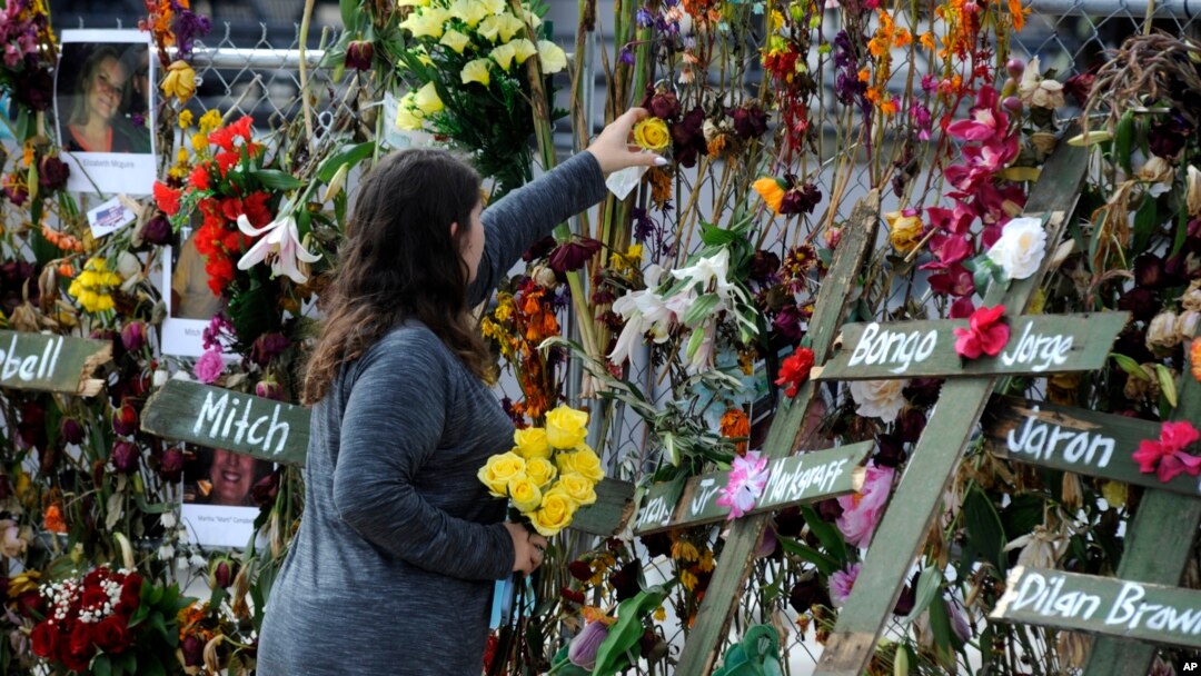 Holly Harmon places a rose into a memorial for victims of Hurricane Ian in Fort Myers, Fla., on Oct. 10, 2022. More than 100 died during the hurricane, with the greatest number in Lee County.