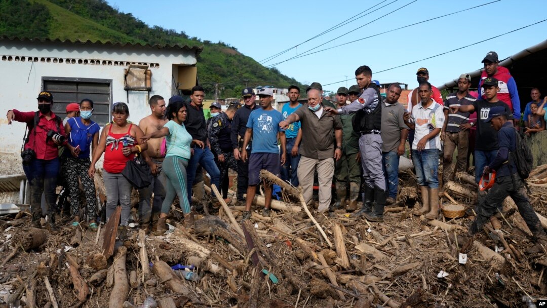 Lawmaker Diosdado Cabello, center right with face mask, tells Venezuela's President Nicolas Maduro where to walk during a visit the area flooded in Las Tejerias, Venezuela, Oct. 10, 2022. A fatal landslide fueled by flooding and rain swept through this town in central Venezuela.
