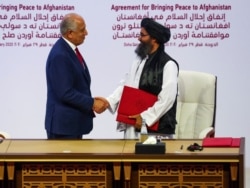 Mullah Abdul Ghani Baradar, the leader of the Taliban delegation, and Zalmay Khalilzad, U.S. envoy for peace in Afghanistan, shake hands after signing an agreement between Afghanistan's Taliban and the U.S. in Doha, Qatar, Feb. 29, 2020.