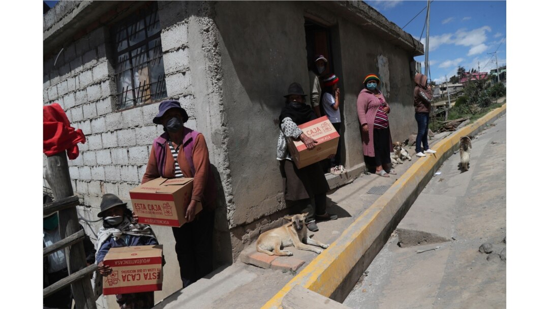 Residents wearing protective face masks hold food boxes distributed by the government during a lockdown to contain the spread of COVID-19, on the outskirts of Quito, Ecuador, May 27, 2020.