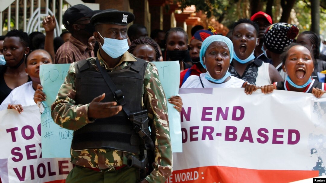 FILE - A policeman stands guard while members of the civil society chant slogans as they demonstrate against gender-based violence to mark International Women's Day in downtown Nairobi, Kenya, March 8, 2022. 