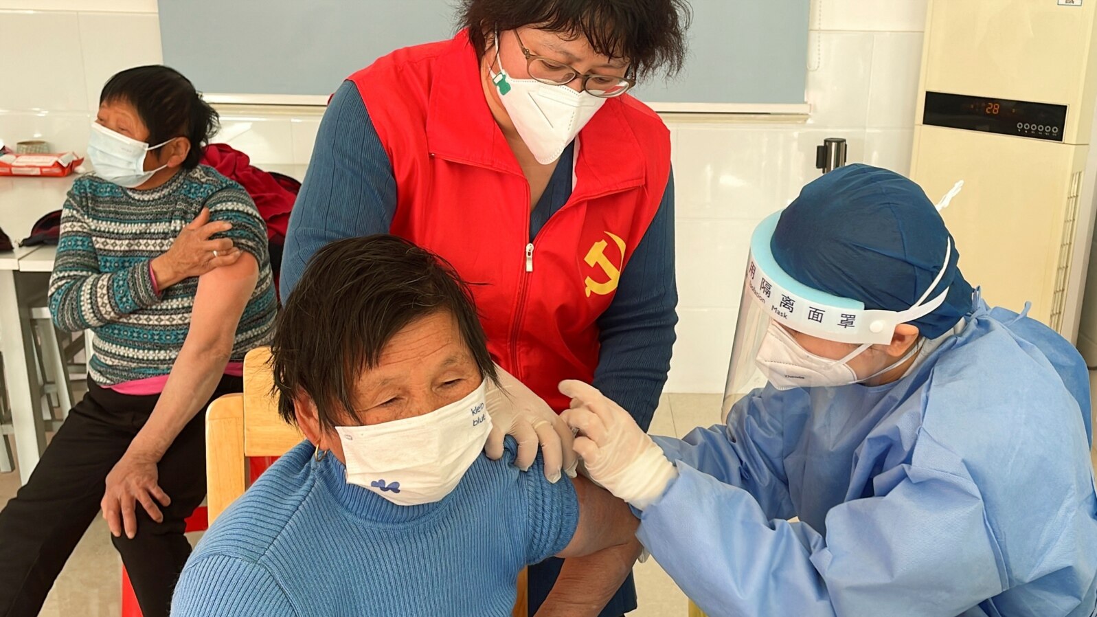 FILE - A medical worker administers a dose of a vaccine against COVID-19 to an elderly resident, during a government-organized visit to a vaccination center in Zhongmin village on the outskirts of Shanghai, Dec. 21, 2022. 