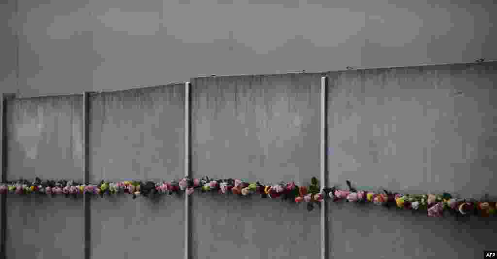 Flowers are laid in the crack of a wall during commemorations to mark the 27th anniversary of the fall of the Berlin Wall, Germany.
