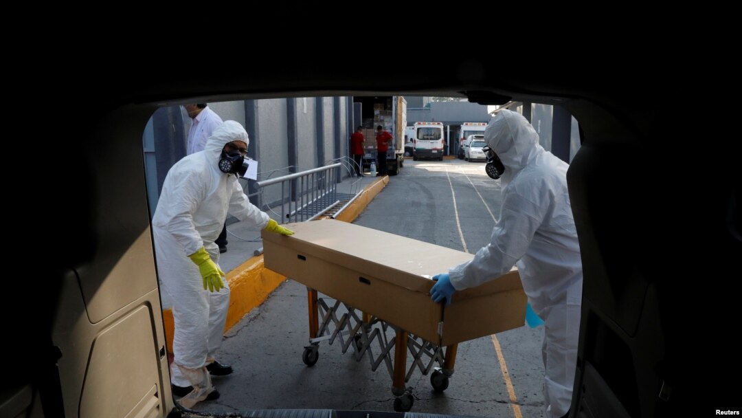 Trabajadores de una funeraria transportan el cuerpo de una persona que murió a causa del coronavirus dentro de un sarcófago de cartón, en la ciudad de México. Junio 5 de 2020.