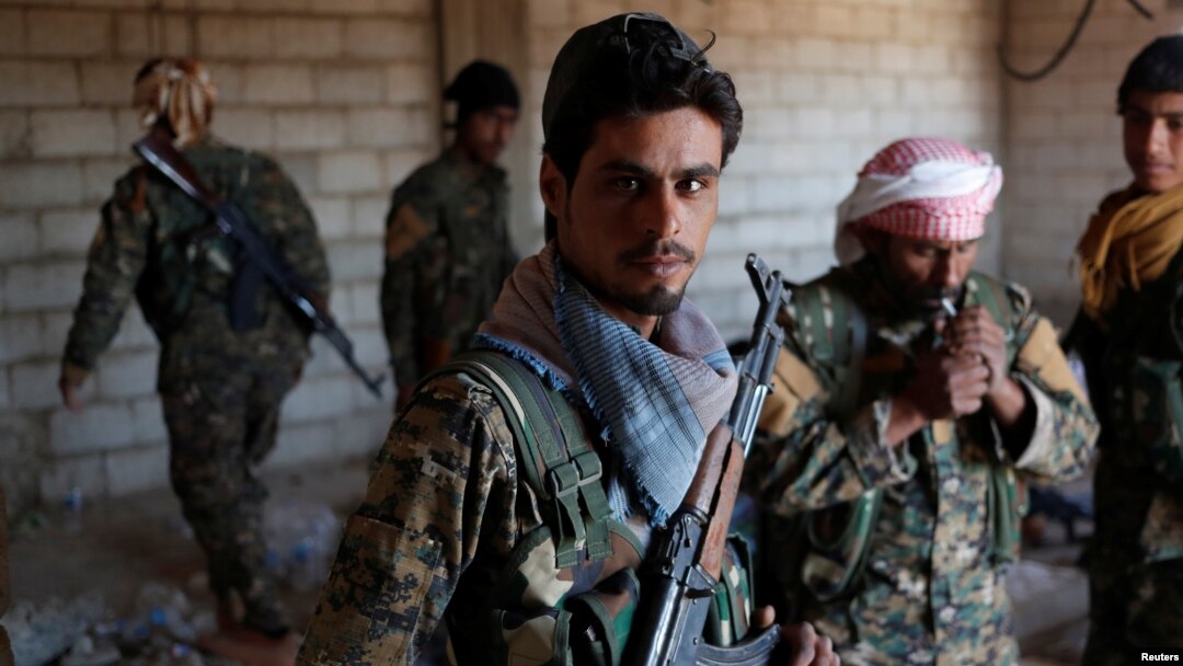 Kurdish fighters from the People's Protection Units (YPG) stand in a house in Raqqa, Syria, June 21, 2017. 