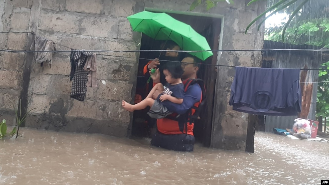 This handout photo taken on Dec. 25, 2022 and received on December 26 from the Philippine Coast Guard shows rescuers evacuating a child from a flooded area in Ozamiz City, Misamis Occidental.