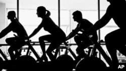 FILE - People exercise on stationary bicycles.