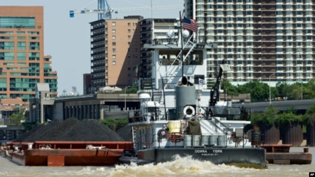 A small, but mighty, tugboat pushes a barge loaded with coal up the Ohio River, past downtown Louisville, Kentucky.