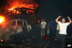 FILE - In this Oct. 13, 2002, file photo, residents and foreign tourists evacuate the scene of a bomb blast in Bali, Indonesia.