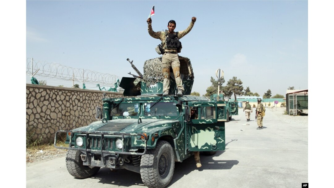 FILE - An Afghan soldier raises his hands as a victory sign, in Kunduz city, Oct. 2, 2015.