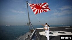Sailors raise the Japanese naval ensign on the deck of Japanese helicopter carrier Kaga before its departure for naval drills in the Indian Ocean, near Jakarta Port, Indonesia September 22, 2018. (REUTERS/Kim Kyung-Hoon)