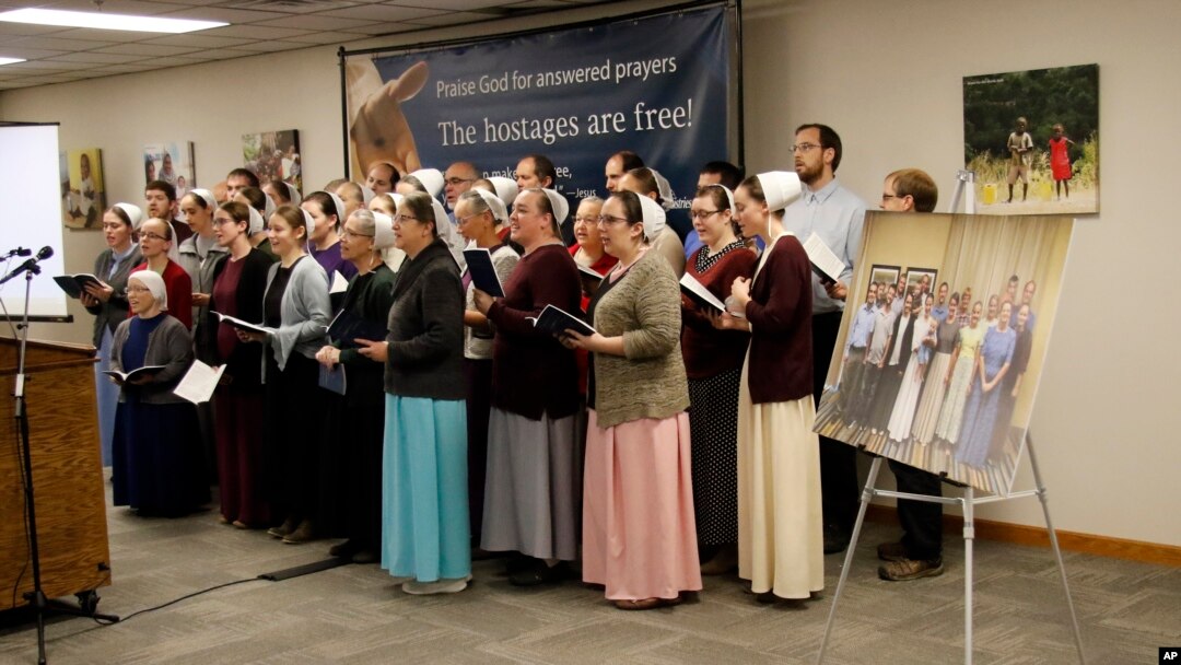 A group photo of the seventeen freed hostages is seen next to the podium as Christian Aid Ministries staff members close a news conference by singing "Nearer My God to Thee" at Christian Aid Ministries home office in Berlin, Ohio, Dec. 20, 2021. 