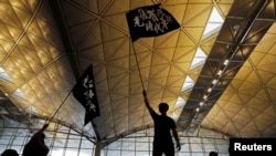 (資料照) 2019年8月12日，香港反“送中”抗議者參加抗議集會。示威者的旗幟上寫的是“光復香港，時代革命”。