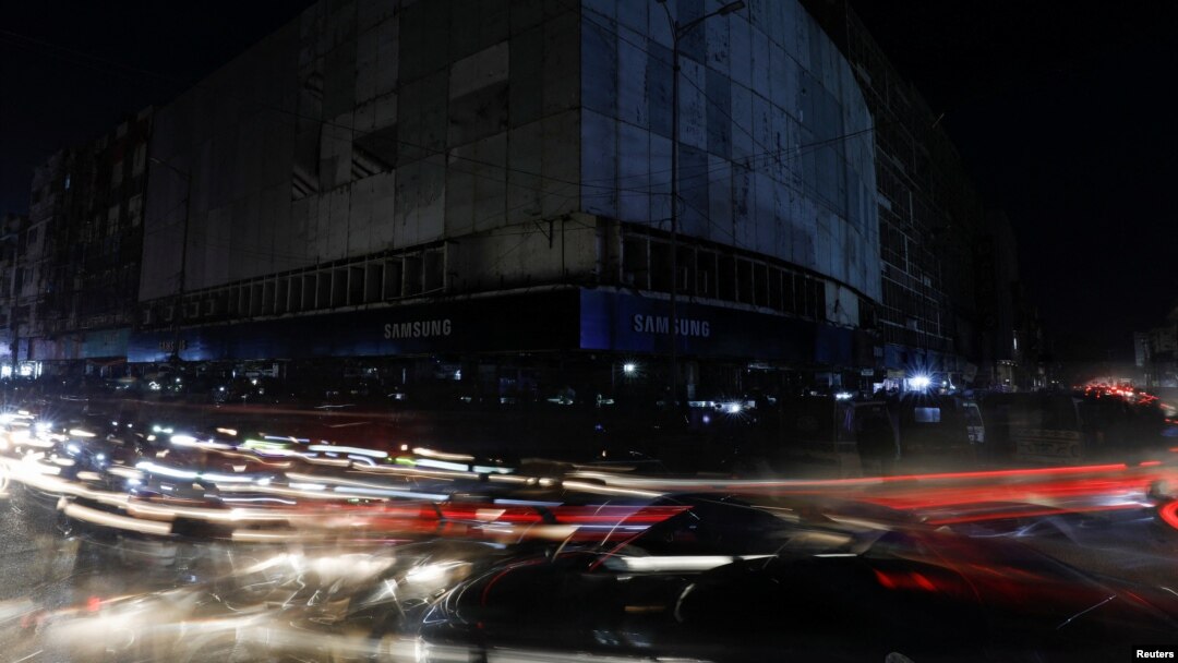 Vehicle lights create light streaks on a road along a market, during a country-wide power outage, in Karachi, Pakistan, Jan. 23, 2023.