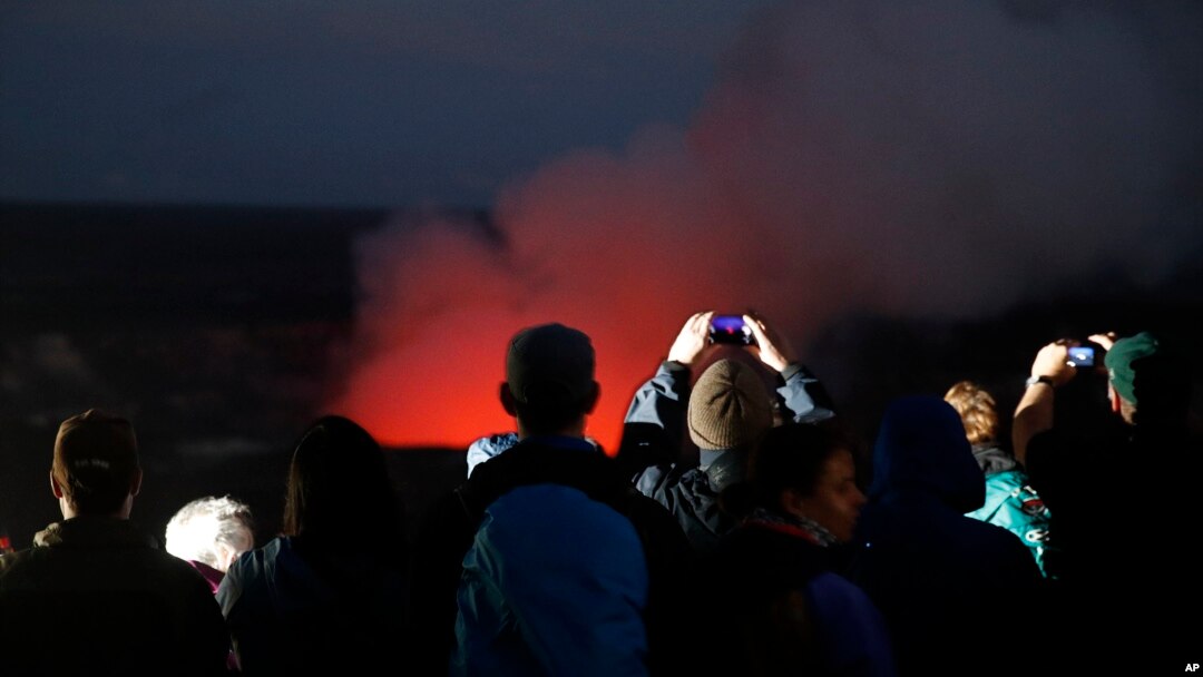 Visitors take pictures as Kilauea's summit crater glows red in Volcanoes National Park, Hawaii, May 9, 2018. Geologists warned Wednesday that Hawaii's Kilauea volcano could erupt explosively and send boulders, rocks and ash into the air around its summit in the coming weeks. 