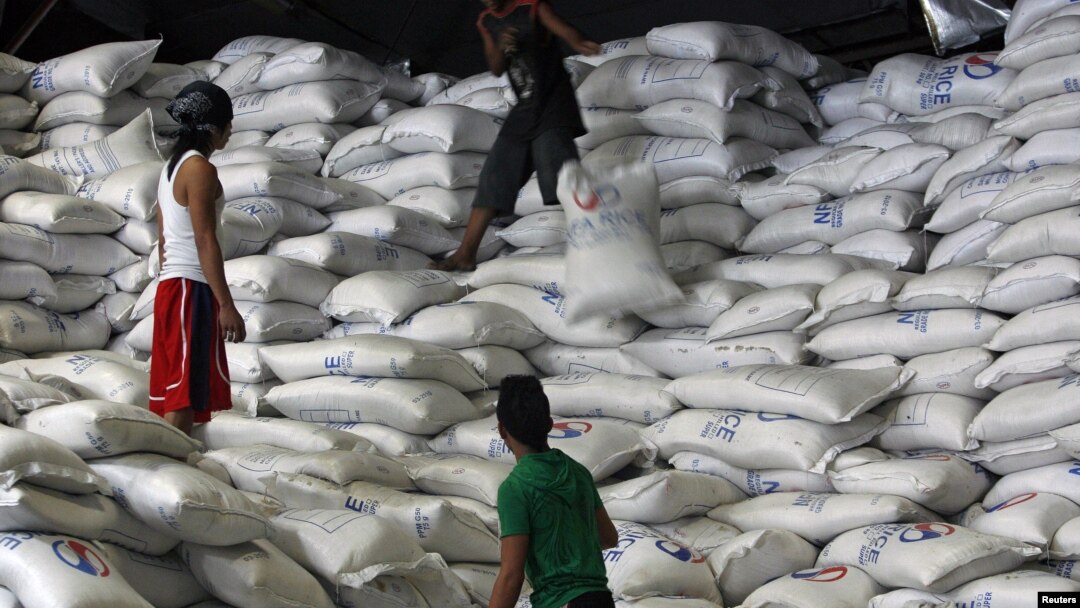 A worker passes a sack of rice to other workers inside a National Food Authority (NFA) warehouse in Taguig City, south of Manila, the Philippines, March 26, 2012. 