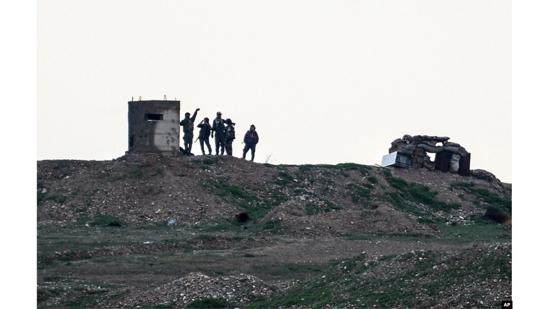 Fighters of People's Protection Units, or YPG, gather at their outpost west of the city of Kobani, northern Syria, Tuesday, Dec. 18, 2018.