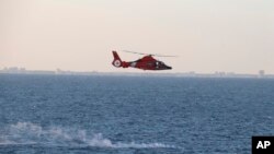 美國海軍提供的圖片顯示美國海岸警衛隊直升機在回收中國高空偵察氣球殘骸行動期間飛過碎片散落區。(2023年2月4日)