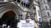 Protesters stand outside The Royal Court of Justice in London that will hear a legal challenge opposing the Home Office's new asylum deal with Rwanda, June 10, 2022.