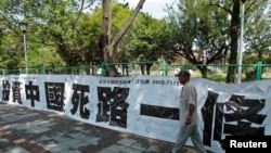 一名男子走過台北街頭懸掛的寫有“投資中國死路一條”字樣的標語。（2012年8月8日）（路透社)