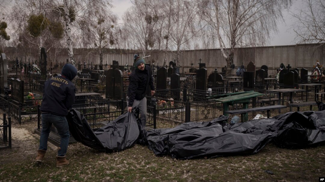 Workers carry the body of people found dead to a cemetery in Bucha, outskirts of Kyiv, Ukraine, April 5, 2022.