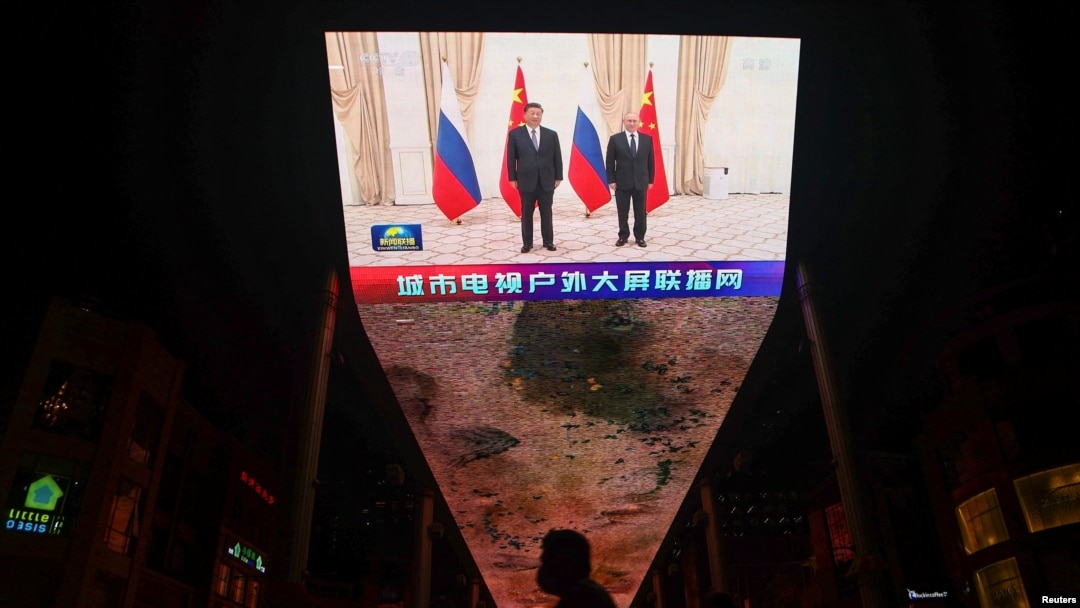 FILE - A giant screen broadcasts news footage of Chinese President Xi Jinping and Russian President Vladimir Putin posing for pictures during a meeting on the sidelines of the Shanghai Cooperation Organization (SCO) summit in Uzbekistan, in Beijing, China, Sept. 16, 2022.